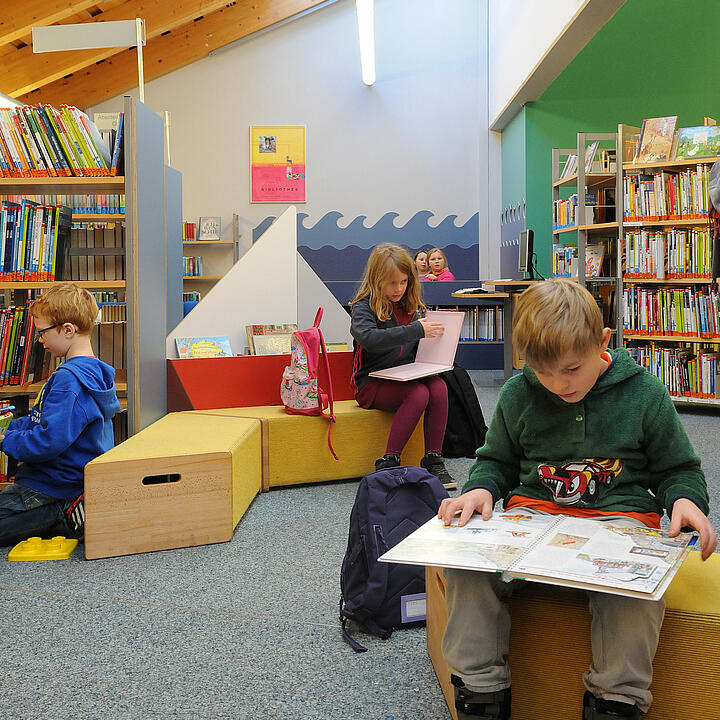 Kinder lesen in einer altersgerecht eingerichteten Abteilung der Bücherei Husum.